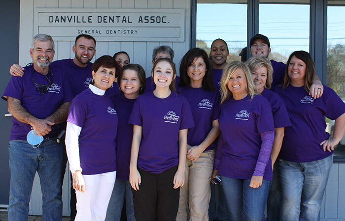 Team photo of dental volunteers in their purple T-shirts