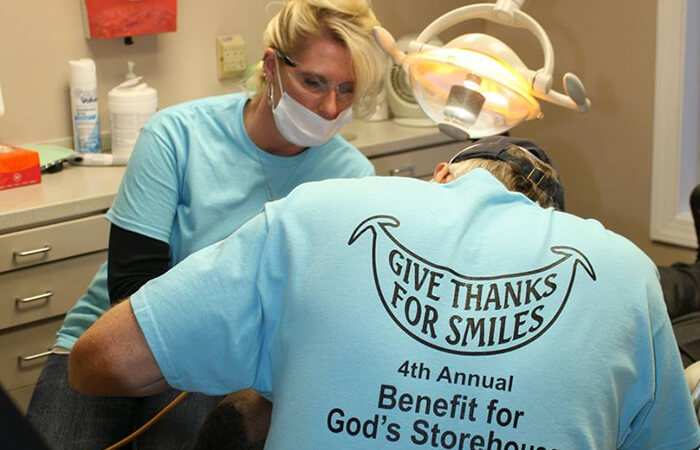 Dental volunteers in their teal shirts helping patients