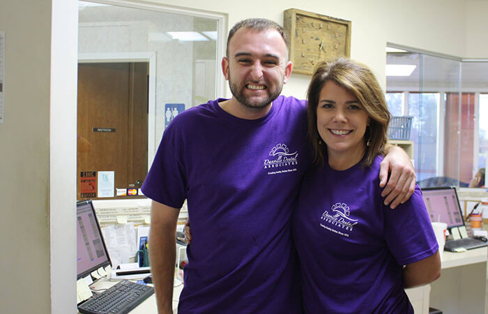 Two dental volunteers smiling in purple T-shirts